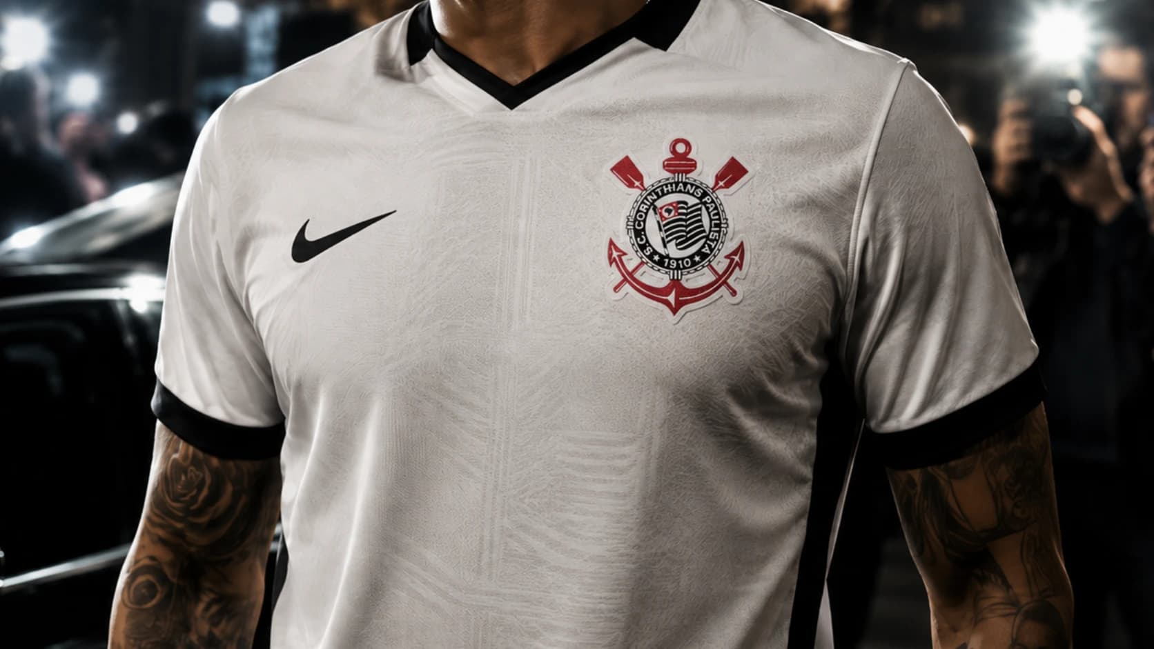 Homem usando camisa branca do Corinthians com escudo em destaque, cercado por flashes de fotógrafos, em imagem de capa sobre famosos corintianos.
